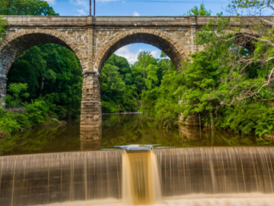 A dam on Wissahickon Creek and old railroad bridge, in Philadelphia, Pennsylvania-Shutterstock_650478007