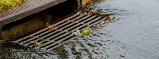 Water gushing from storm sewer following very heavy rainfall of the road after heavy rain-Shutterstock_1475580638