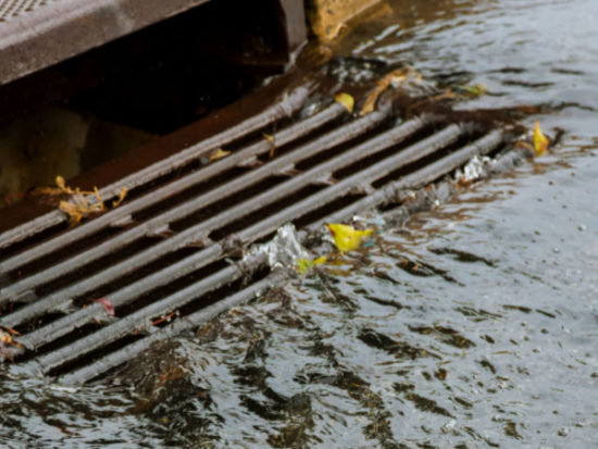 Water gushing from storm sewer following very heavy rainfall of the road after heavy rain-Shutterstock_1475580638