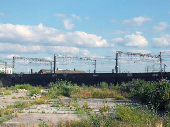 a large unused urban brownfield site with open land covered in cracked overgrown concrete awaiting development in leeds england-Shutterstock_1474051175
