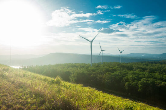 Electric wind turbine view with blue sky above the dam