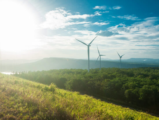 Electric wind turbine view with blue sky above the dam