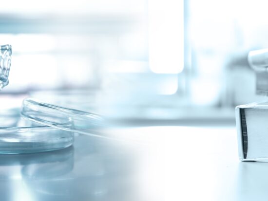 Hand,Of,Scientist,Holding,Flask,With,Petri,Dish,And,Stack