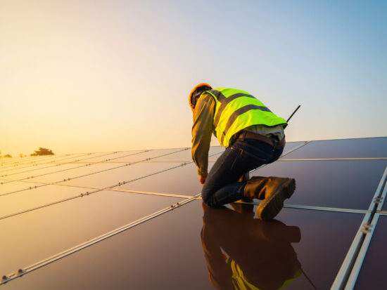 Portrait of engineer man or worker, people, with solar panels or solar cells on the roof in farm. Power plant with green field, renewable energy source in Thailand. Eco technology for electric power.