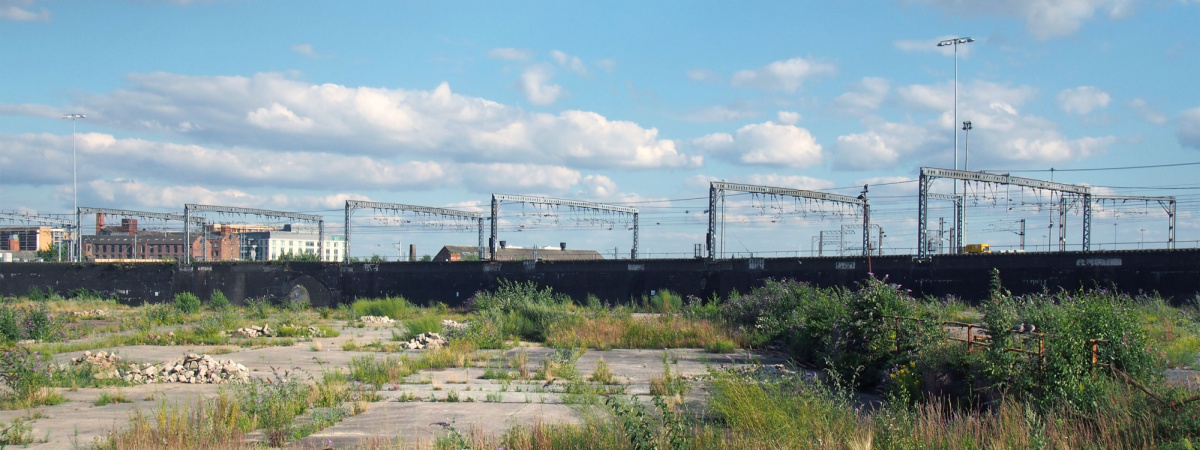a large unused urban brownfield site with open land covered in cracked overgrown concrete awaiting development in leeds england-Shutterstock_1474051175