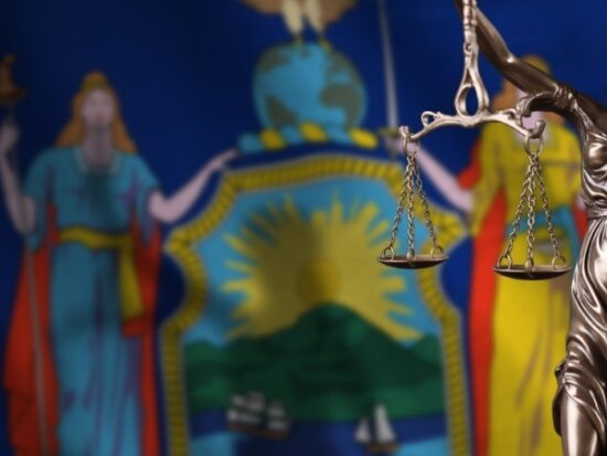 New York US state flag with statue of lady justice and judicial scales-Shutterstock_2242551935